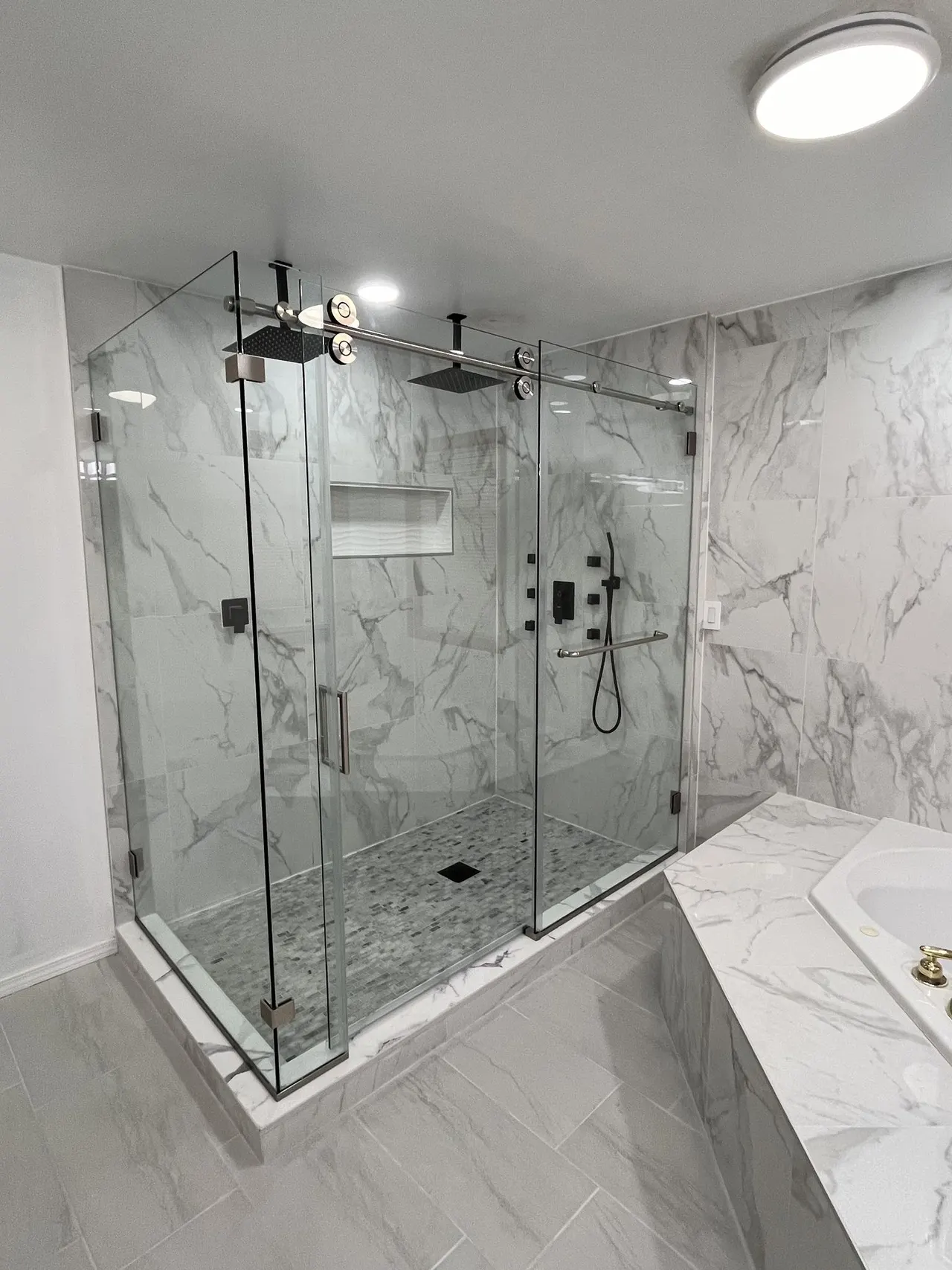 Large frameless glass shower enclosure with brushed-nickel hardware and dual rain shower heads, real Mesko Glass installation.